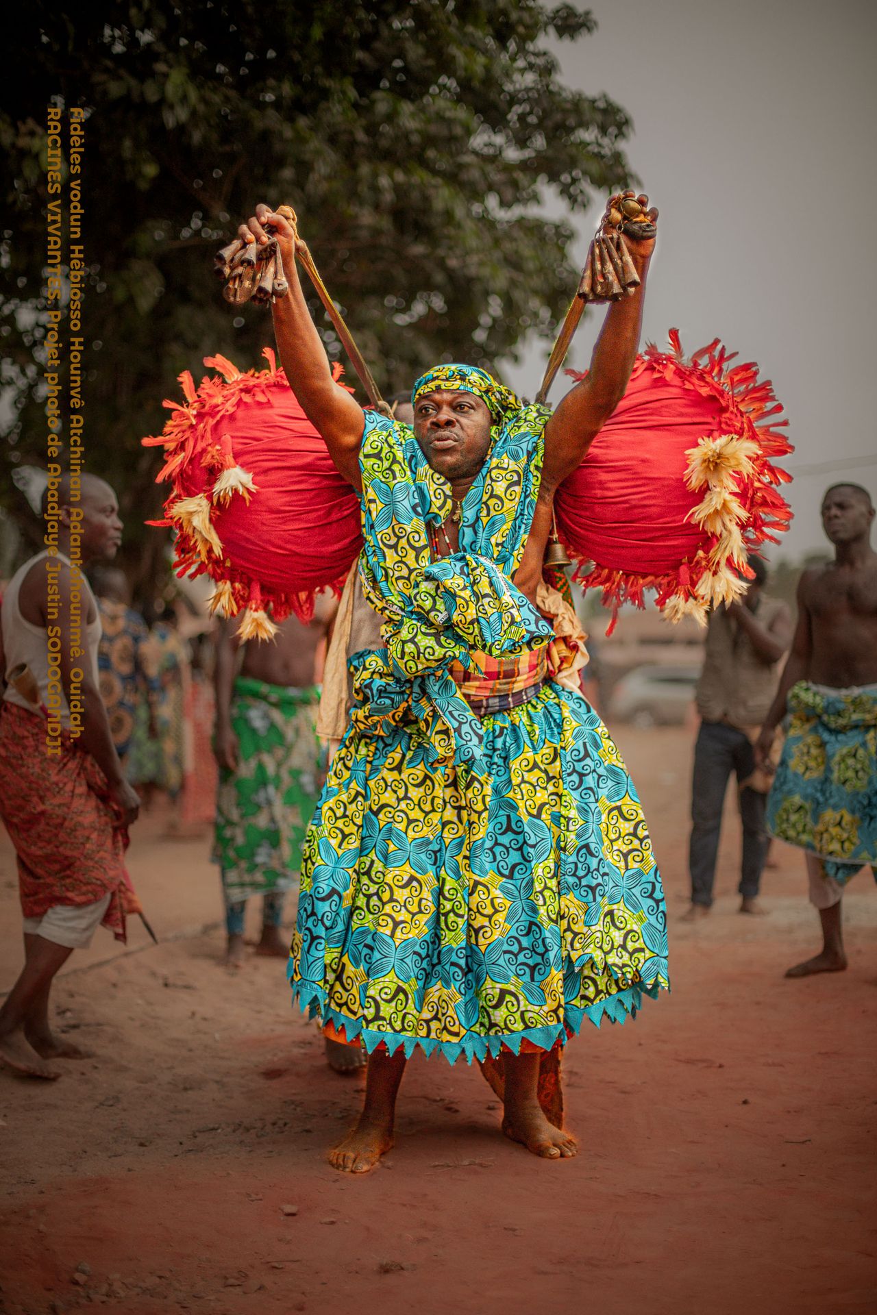 À Ouidah, berceau du vodoun, Hêbiosso ADANTOHOUNME, de la lignée DEHOUE AGLANMETOKA, a établi le premier couvent Hêbiosso Hounvè, introduisant le culte du Vodoun Atchina.  Aujourd'hui, la famille SODOGANDJI perpétue cet héritage ancestral en tant que gardienne mondiale de cette tradition.  À travers mon projet « RACINES VIVANTES », je célèbre ces figures emblématiques et la richesse de notre patrimoine.  © Abadjayé Justin, Ouidah, 2024- 2025. TOUS DROITS RÉSERVÉS